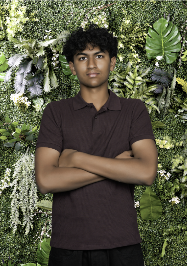 Ritham standing with arms crossed in front of a wall of plants