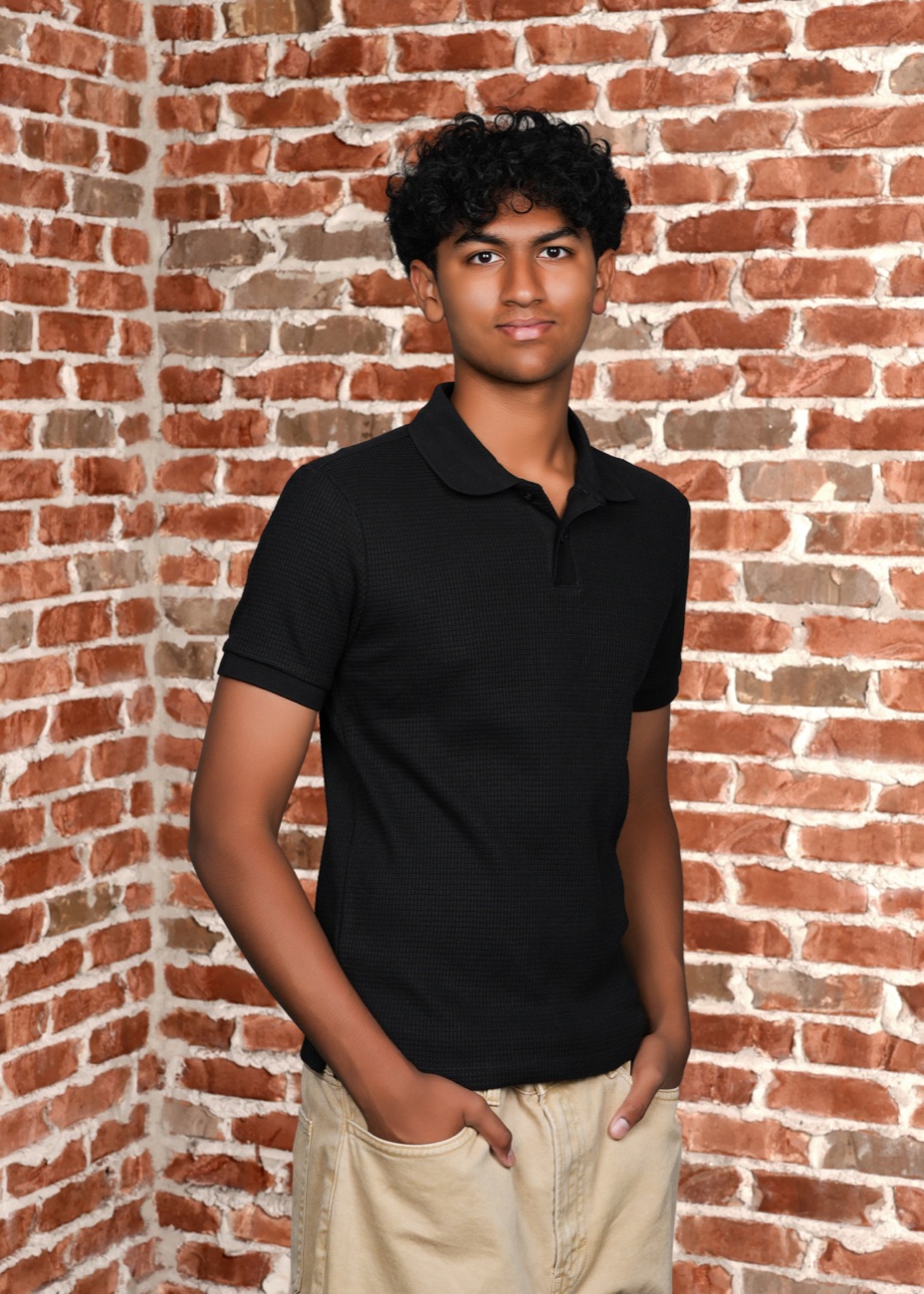 Ritham leaning against a red brick wall